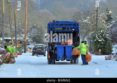 Dustcart autocarro e binmen sulla neve ghiacciata coperto strada residenziale Foto Stock