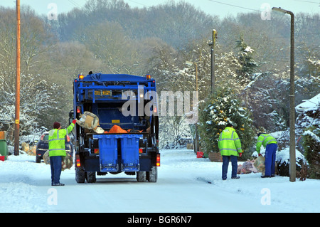 Dustcart autocarro e binmen sulla neve ghiacciata coperto strada residenziale Foto Stock