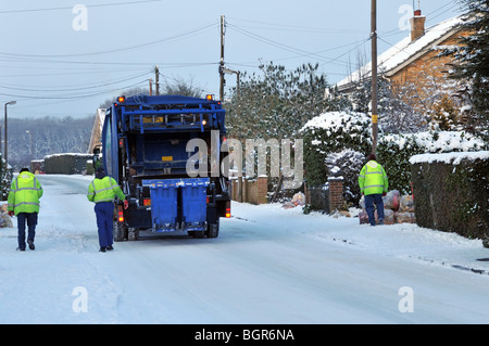 Dustcart autocarro e binmen sulla neve ghiacciata coperto strada residenziale Foto Stock