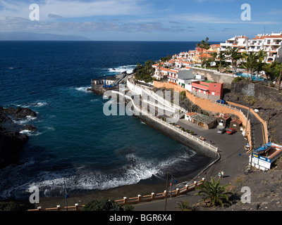 Playa Puerto Santiago piccola spiaggia e porto di pesca in Tenerife con l'isola di La Gomera all'orizzonte Foto Stock