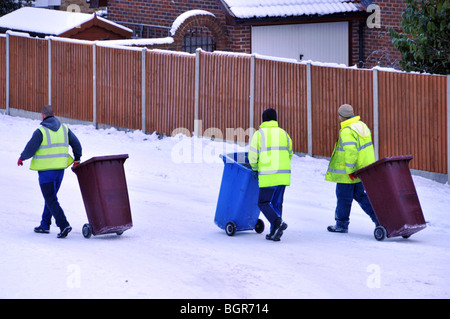 Binmen sulla neve ghiacciata coperto strada residenziale Foto Stock