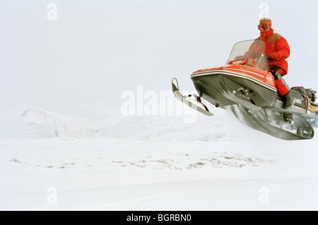 Un uomo salta con una motoslitta Foto Stock