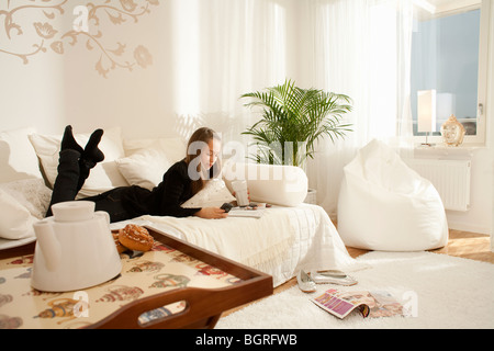 Ragazza adolescente giacente in un lettino in un interni Scandinavo, Svezia. Foto Stock