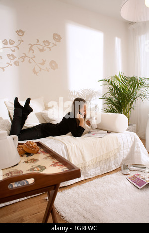 Ragazza adolescente giacente in un lettino in un interni Scandinavo, Svezia. Foto Stock