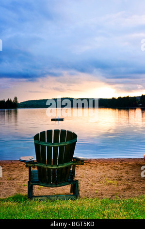 Sedia in legno sulla spiaggia del lago al tramonto Foto Stock