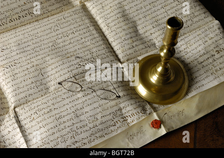 Antichi documenti, scritto in inglese, occhiali e candelabro in ottone, visualizzato su un cuoio sormontato scrivania Foto Stock