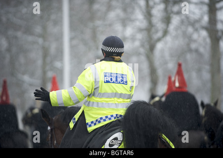 Poliziotta a cavallo nella neve chaperoning regina della Royal Life Guard cavalleria Foto Stock