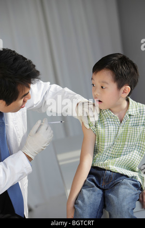 Medico dando giovane ragazzo in un'iniezione. Foto Stock