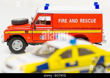 Primo piano di giocattolo British Fire and Rescue veicolo con auto di polizia in primo piano Foto Stock