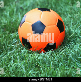 Orange soccer ball in appoggio su erba verde Foto Stock