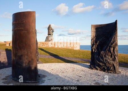 RNLI Royal Charter naufragio memorial sculture con statua del timoniere Richard (Dic) Evans al di là. Moelfre, Anglesey, Galles del Nord, Regno Unito Foto Stock