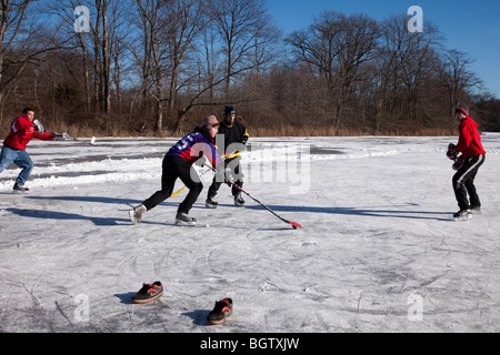 Ragazzi giocare hockey su ghiaccio su un laghetto congelato Foto Stock
