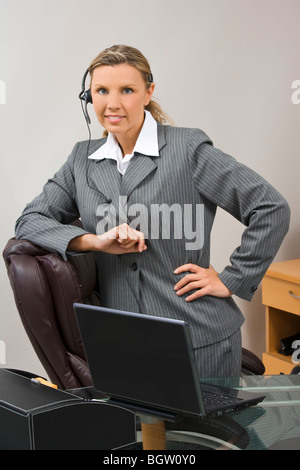 Imprenditrice caucasica nei suoi primi 30s accanto alla scrivania e sorridente Foto Stock