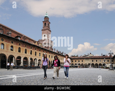 Giovani donne con del Bramante torre sul Castello Sforzesco in Piazza Ducale di Vigevano Lombardia Italia con portici o portici Foto Stock