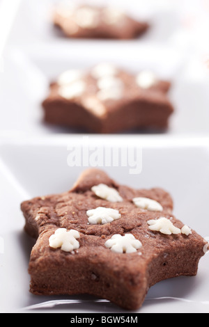 In casa a forma di stella biscotti al cioccolato con fiocchi di neve di zucchero sulla parte superiore Foto Stock