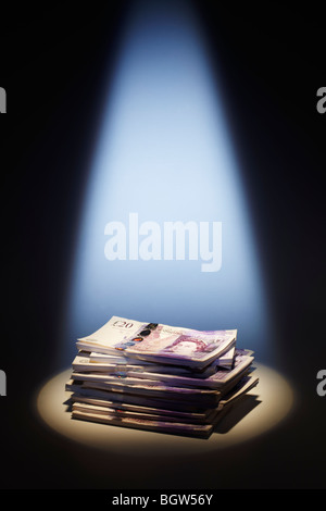 Pila di venti Pound note sotto i riflettori Foto Stock