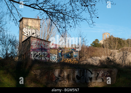 Coperto di graffiti vestigio industriale e la romanica chiesa di Saint Etienne d'Issensac, Francia meridionale Foto Stock