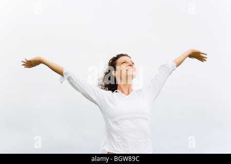 Donna sorridente e felice con le braccia aperte godendo di spirito libero Foto Stock