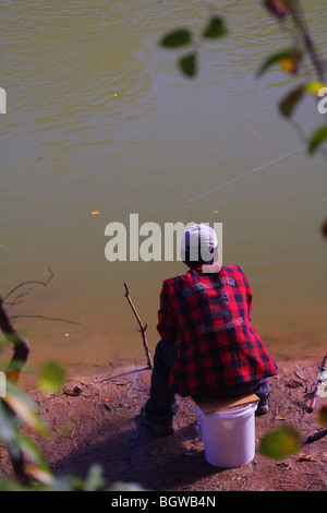 Vista posteriore del pescatore RED FLANNEL SHIRT seduti sulla benna di pesca in fiume Chattahoochee GEORGIA nessun modello di rilascio Foto Stock