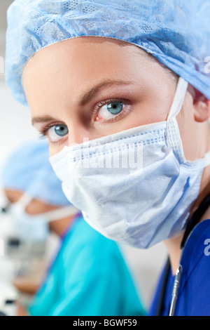 Una bionda femmina o medico ricercatore scientifico o medico di indossare una mascherina chirurgica in un laboratorio con il suo collega asiatica Foto Stock