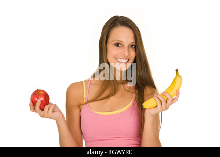 La donna caucasica tenendo una mela e una banana cercando di decidere che uno a mangiare Foto Stock