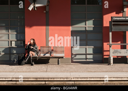 Giovane donna in attesa di un treno in una stazione ferroviaria nel sud della Francia Foto Stock