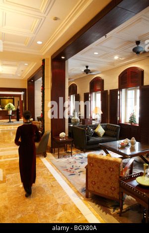 Rapporti con gli ospiti il personale a piedi attraverso la lobby dell'Hotel Metropole Hanoi, Vietnam. Foto Stock