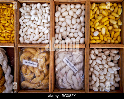 Silkworm cocoon e seta tessuta Filo Bombice Mori sul visualizzatore in corrispondenza di una seta Thailandese shop. Thailandia SUDEST ASIATICO Foto Stock