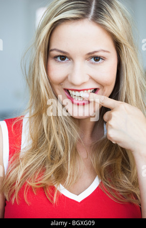 Giovane donna puntando verso i suoi denti Foto Stock