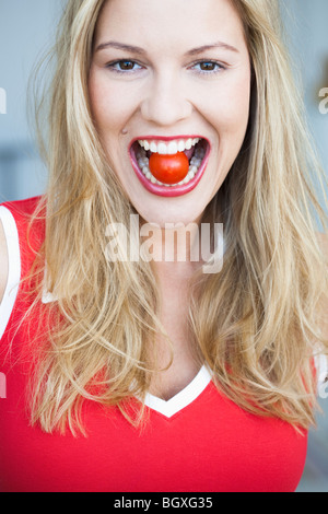 Giovane donna di pomodoro da masticare Foto Stock