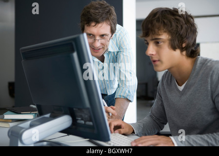 Maestro sorridente, rivedendo studente di lavoro sul computer Foto Stock