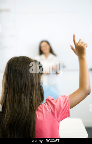 Scuola elementare studente alzando la mano in classe, vista posteriore Foto Stock