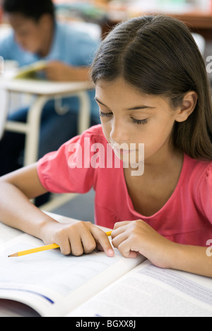 Femmina scuola elementare studente facendo incarichi Foto Stock