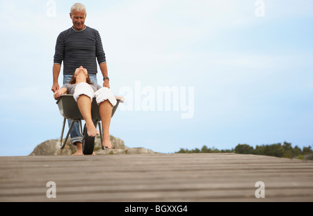 Donna di mezza età spinto nella ruota barrow Foto Stock