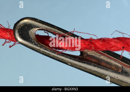 La cruna di un ago con filo rosso. Foto Stock