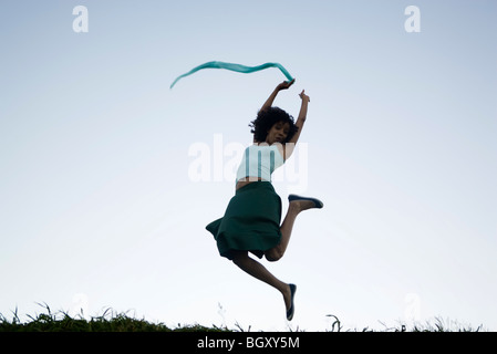 Spensierato giovane donna che saltava, sciarpa in mano il fanalino di coda Foto Stock