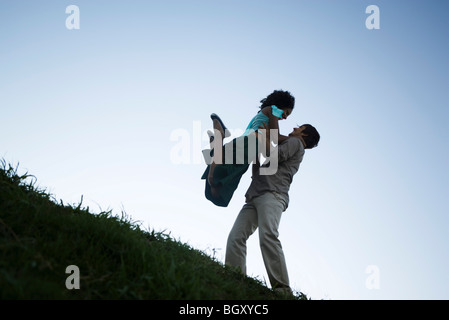 Coppia giovane, donna jumping in uomo di braccia Foto Stock