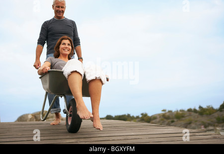 Donna di mezza età spinto nella ruota barrow Foto Stock