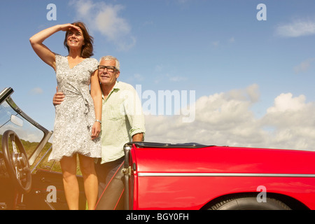 Coppia senior con auto sportiva, osservando Foto Stock