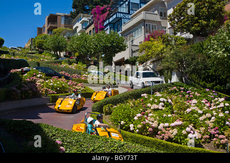 Turisti andare affitto auto e godere i colpi di scena e svolte di Lombard Street - SAN FRANCISCO, CALIFORNIA Foto Stock