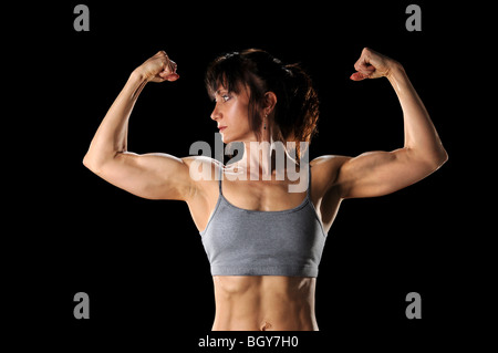 Donna matura la flessione di muscoli isolate su sfondo nero Foto Stock