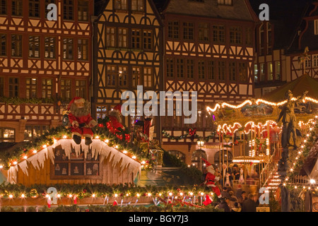 Decorate Christkindlmarkt (Mercatino di Natale) si spegne e il merry-go-round impostare di fronte agli edifici in Römerberg (Municipio Foto Stock