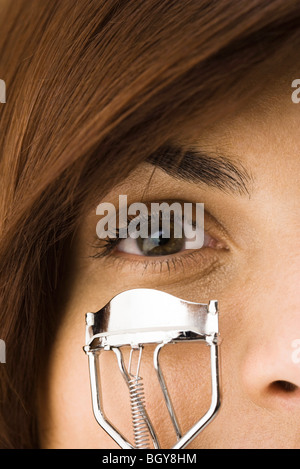 Giovane donna utilizzando arricciatore ciglia Foto Stock