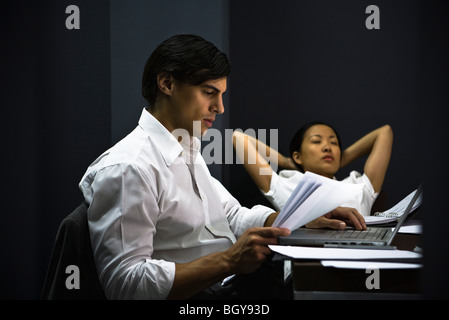 Uomo in ufficio a lavorare in ritardo, collega il relax in background Foto Stock