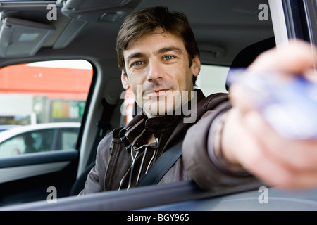 Metà di uomo adulto in drive-thru consegnando la carta di credito al check-out addetto alla finestra Foto Stock