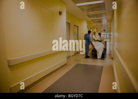 I lavoratori del settore sanitario il trattamento paziente sulla barella nel corridoio dell'ospedale Foto Stock