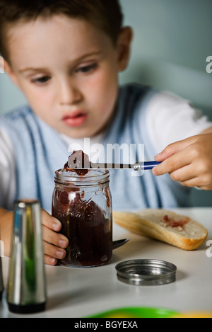 Ragazzo preparare snack di marmellata e pane Foto Stock