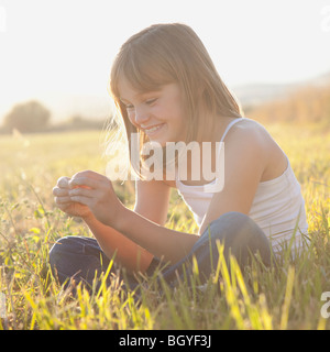 Ritratto di giovane ragazza seduta nel campo Foto Stock