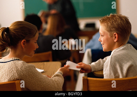 Gli studenti passando nota in aula Foto Stock