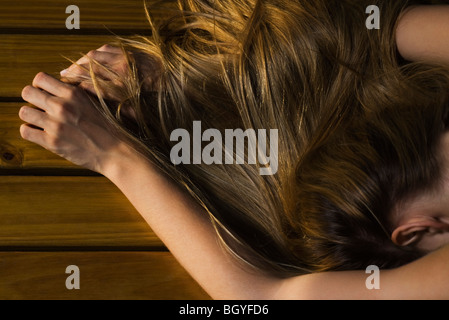 Donna disteso a faccia in giù sul pavimento, capelli lunghi che coprono il braccio, ritagliato Foto Stock